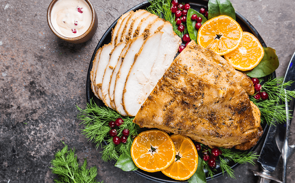healthy roast turkey breast with christmas themed oranges and pomegranate seeds