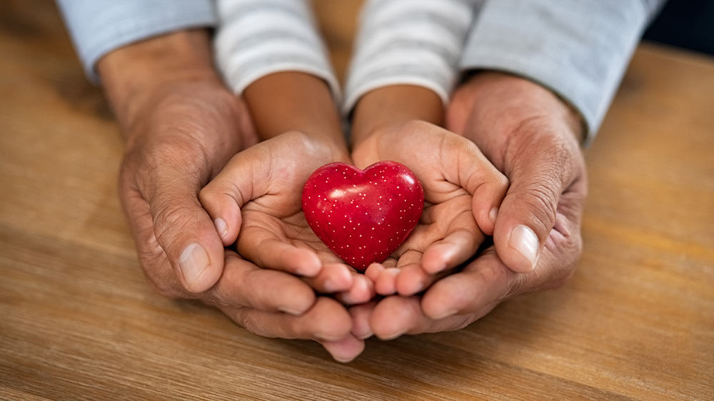 adult and child holding a heart in hands