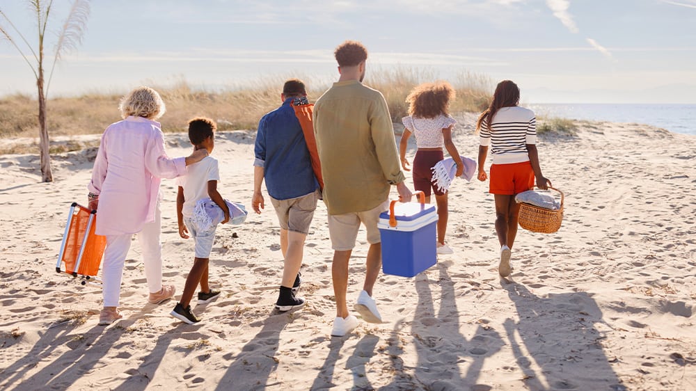 multi generational family with picnic baskets at beach