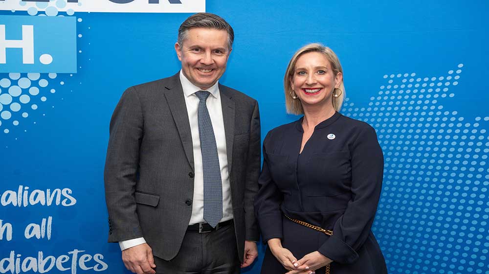 Health Minister Mark Butler and Justine Cain stand against a blue background.
