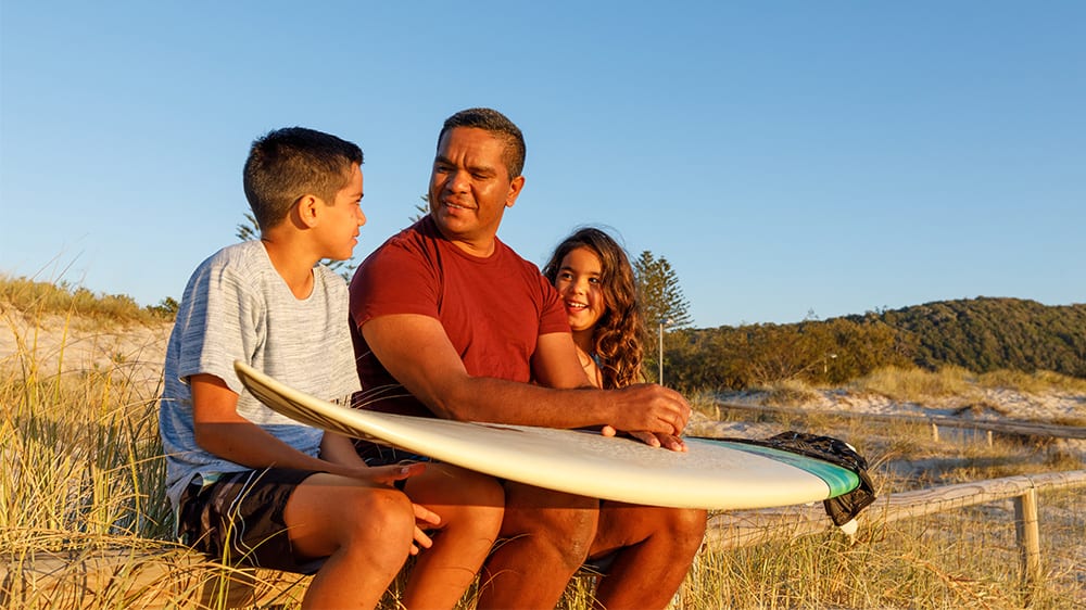 dad and kids with a surf board