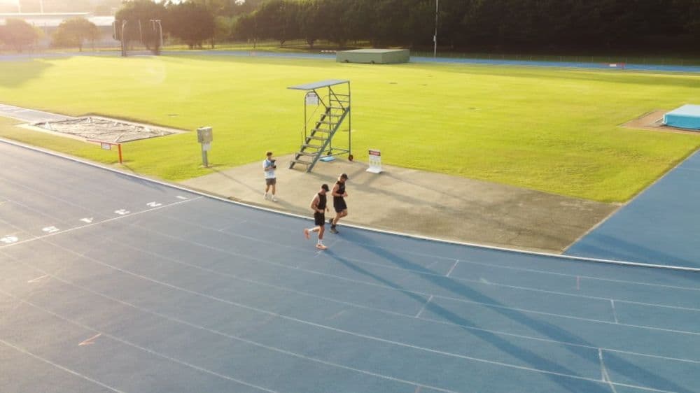 Brodie Sargent training on an athletics track with friends, ariel view