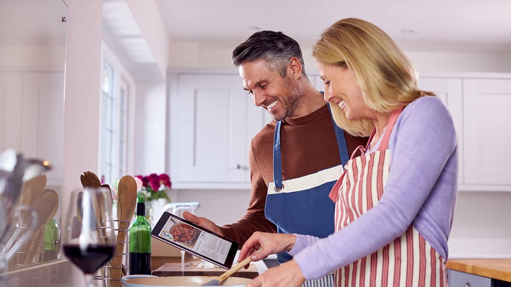 Couple cooking together using a recipe on a tablet device