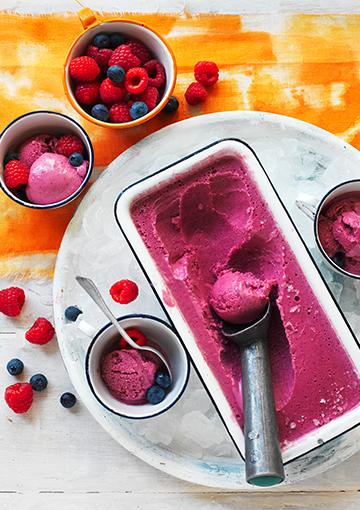frozen yoghurt with berries in a white serving dish and ice cream scoop