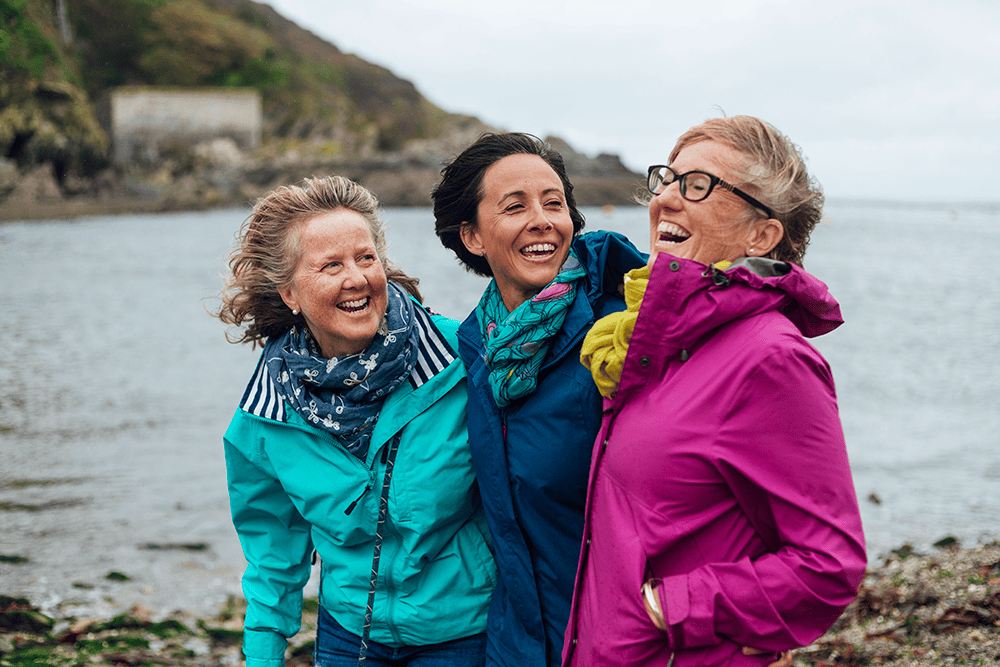 3 laughing women by a lake on a windy day
