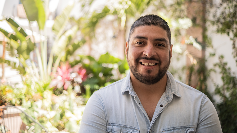 happy man in front of a tropical looking garden