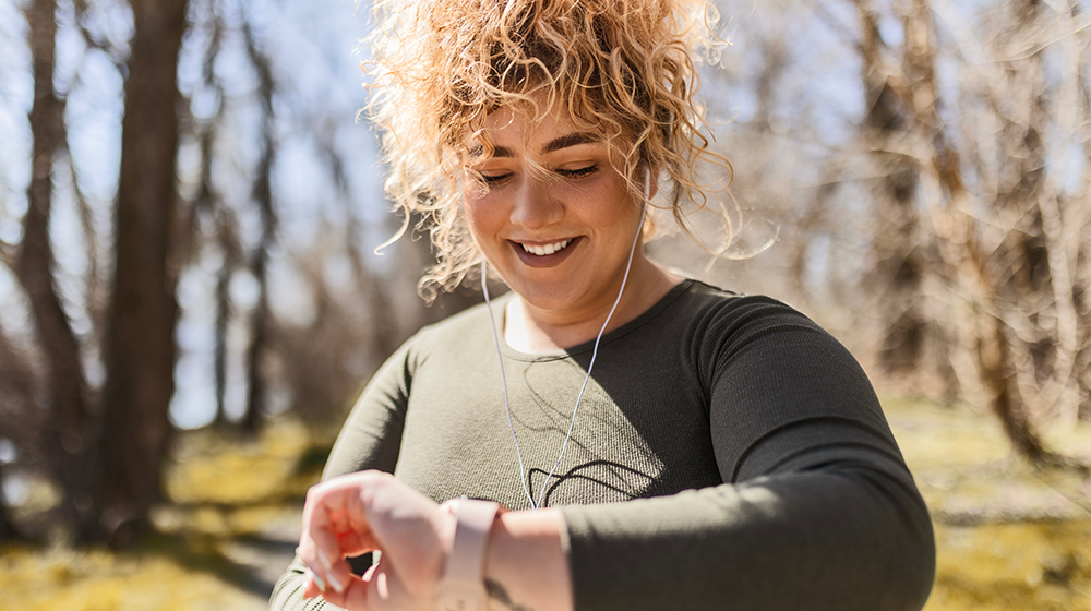 happy woman exercising outside checking her watch