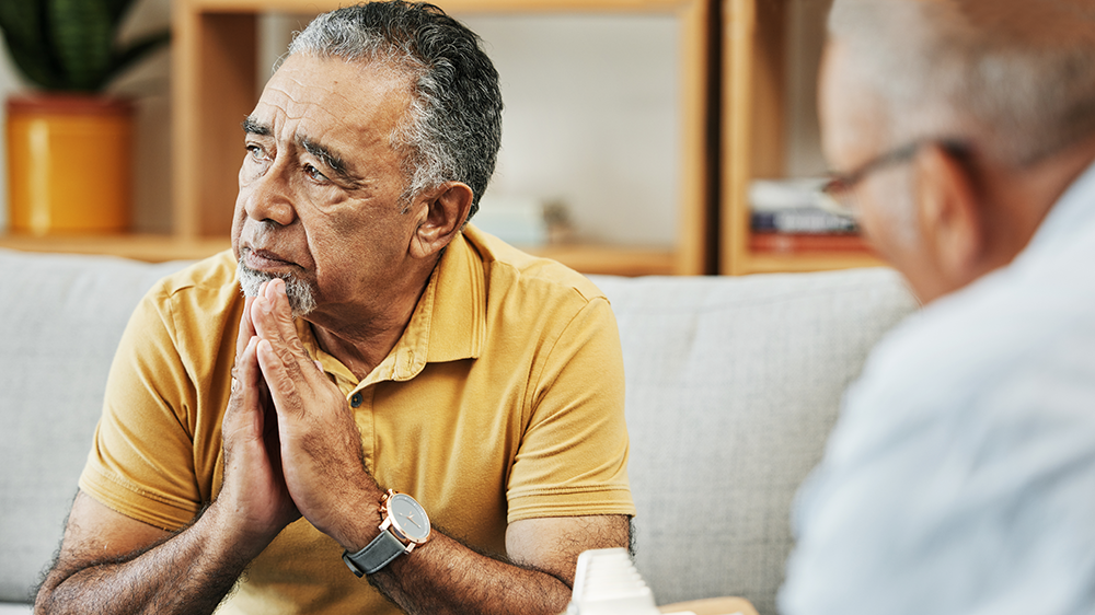 man in yellow top looking contemplative at psychology appointment