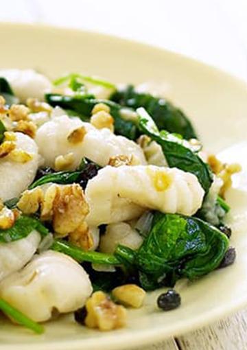 Gnocchi with Spinach and Walnuts and currents on a white plate