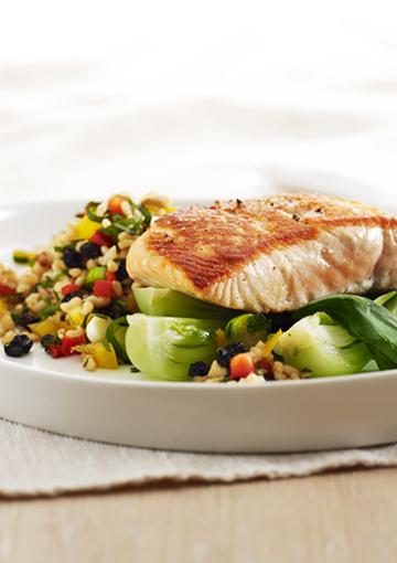 Grilled Salmon on a bed of vegetables and rice on a white plate