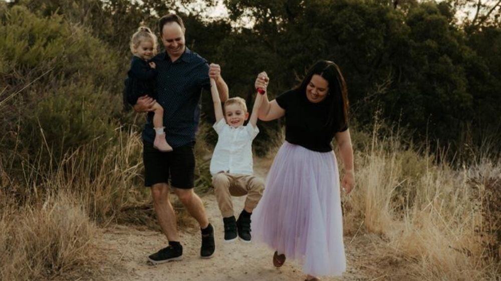 Lauren Cusack lifting her son up with her husband who is holding their daughter on a beach track