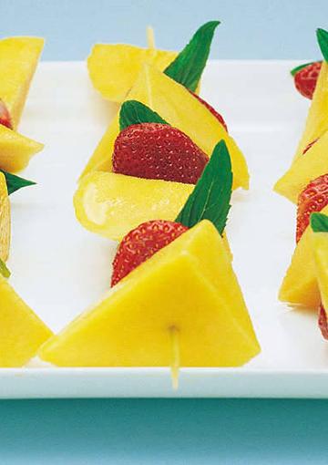mango and strawberry kebabs with mint on a white tray