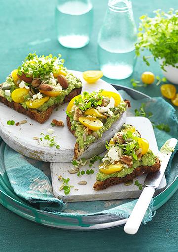 pea and hummus toast topped with yellow cherry tomatoes, seeds and cress