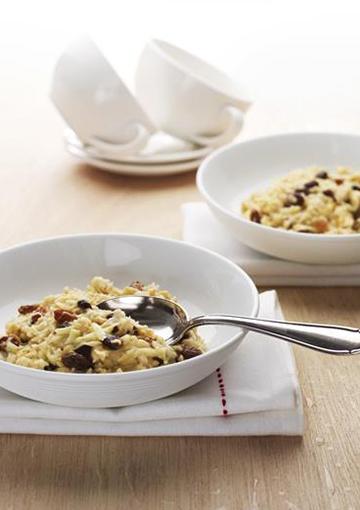 Porridge with dried fruits topped with cinnamon in white bowls