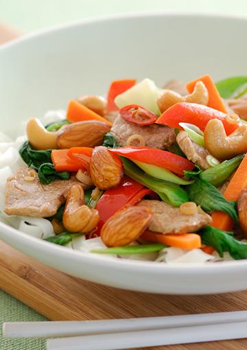 Pork with almonds, cashews and mixed vegetables on a bed of rice noodles