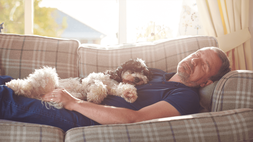 man sleeping on sofa with dog
