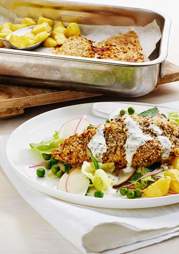crusted chicken with potatoes and peas topped with a yoghurt dressing
