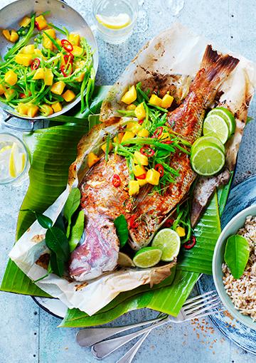 Grilled whole snapper topped with mango chilli snow peas in a banana leaf