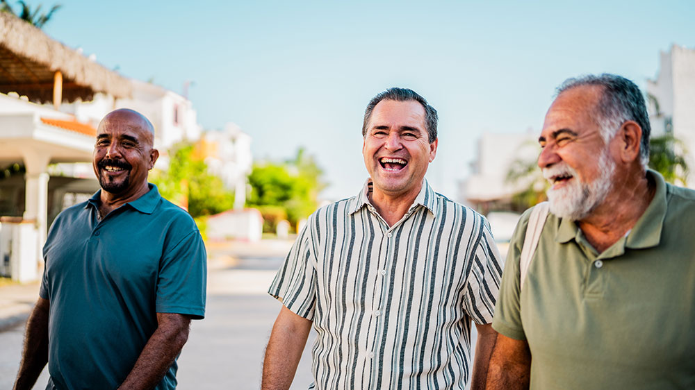 Three older men walking down the street laughing