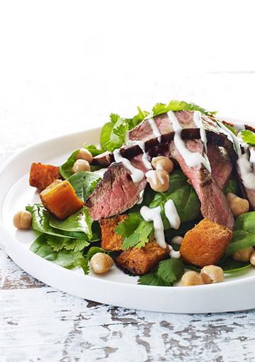 Spinach salad with pumpkin, beef and chickpeas topped with yoghurt dressing