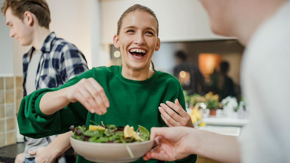 Woman smiling as she squeezes lemon juice on a salad