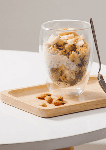 overnight oats with almonds and bananas with a spoon in a glass