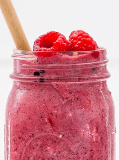 Berry Oat Smoothie in a jar with raspberries and a paper straw
