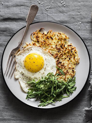 Potato latkes, fried egg and arugula - delicious healthy breakfast or snack.