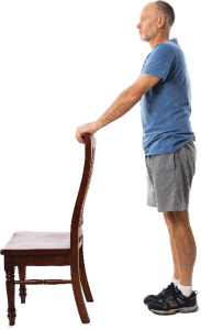 man standing holding onto back of chair