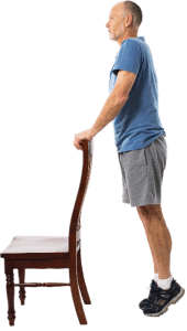 man standing on tiptoe holding the back of a chair