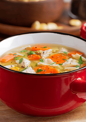 chicken and veg soup in red bowl