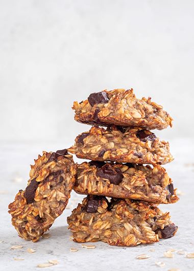 Chocolate oat protein cookies stacked up on a bench