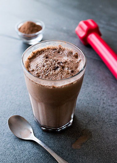Chocolate Protein Shake Smoothie with Whey Protein Powder and Red Dumbbells.