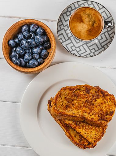 Cinnamon and maple French toast on a plate, with blueberries in a bowl next to it