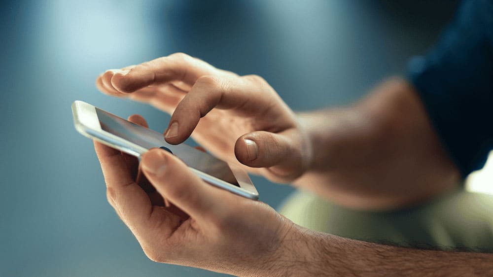 close up of a man's hands using a mobile phone