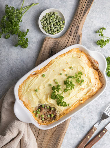 Shepherd's Pie with ground beef, potato and cheese on wooden cutting board