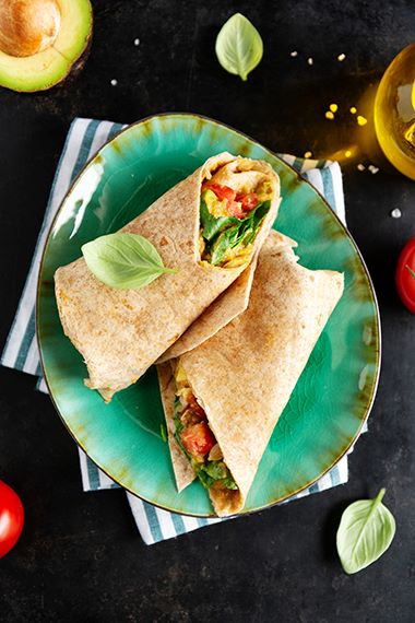 Egg and veggie breakfast wrap sitting on plate