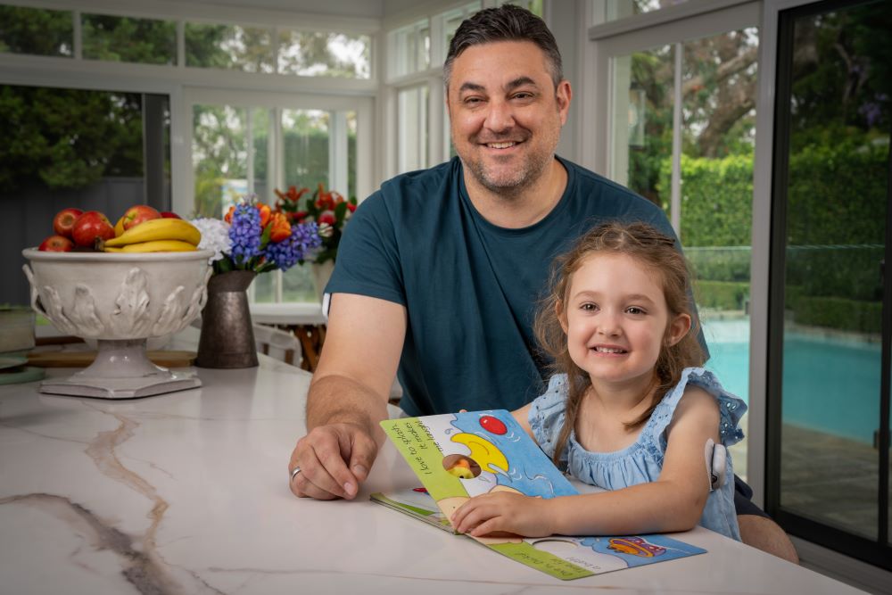 Father and daughter reading picture book at table