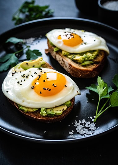 Sunny side up eggs on toasted bread with avocado