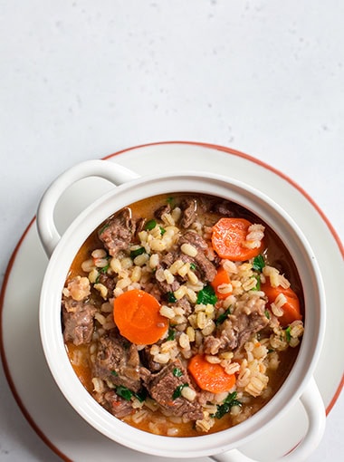 Homemade beef and barley soup. White background.