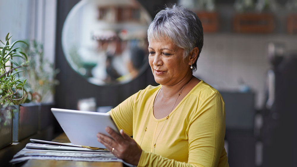 Serene looking woman in a yellow jumper looking at her laptop
