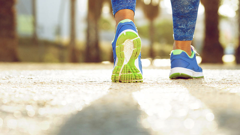 Walking mindfully, green and blue trainers on pavement