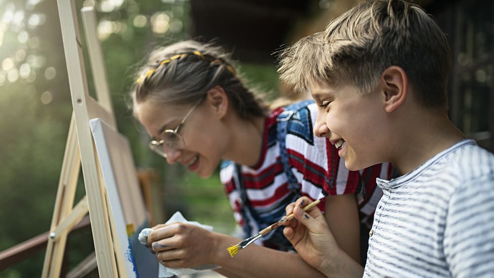 Kids painting outside on an easel