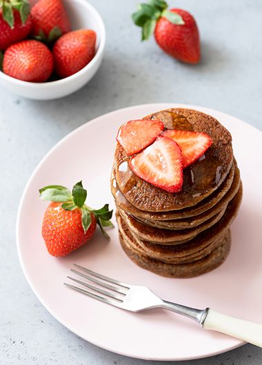 Chocolate pancakes with strawberries stacked on a plate
