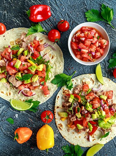 Tuna tacos with tomato and avocado, ready to be eaten, resting on a serving platter