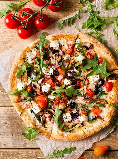 Vegetable pizza on baking paper, ready to serve