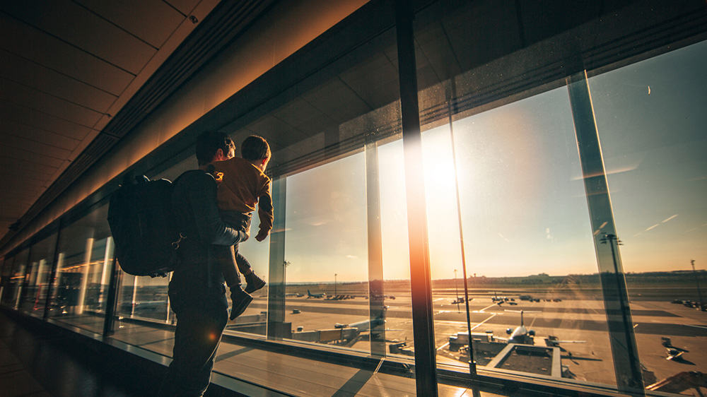 man and son at airport looking at planes through the window