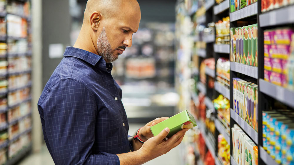 Man standing in a supermarket looking at a food label
