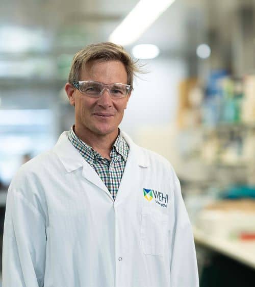 Man standing in a laboratory, wearing a labcoat and facing camera