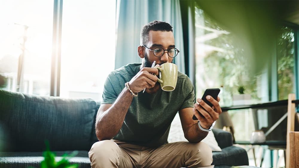 man looking at phone while drinking tea